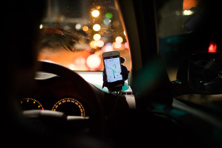a cell phone showing a map sits on a dashboard attachment in a car