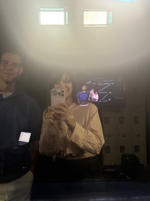 photo of a woman taking a selfie with screens in the background.