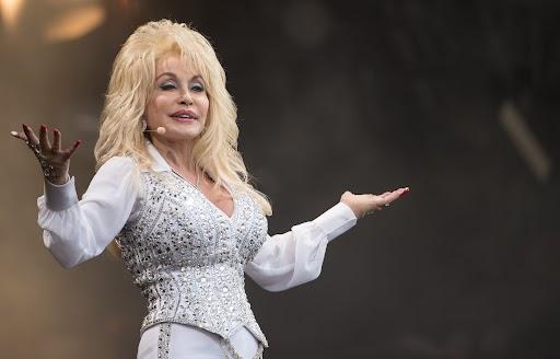 a blonde woman with big hair stands on stage during a concert