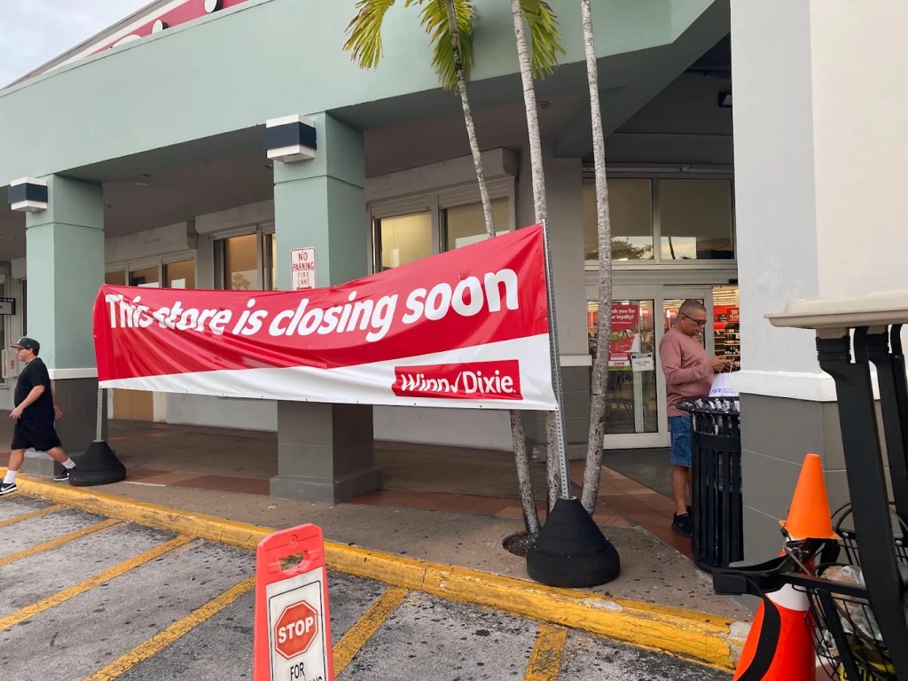 the outside of grocery store with a large red closing banner