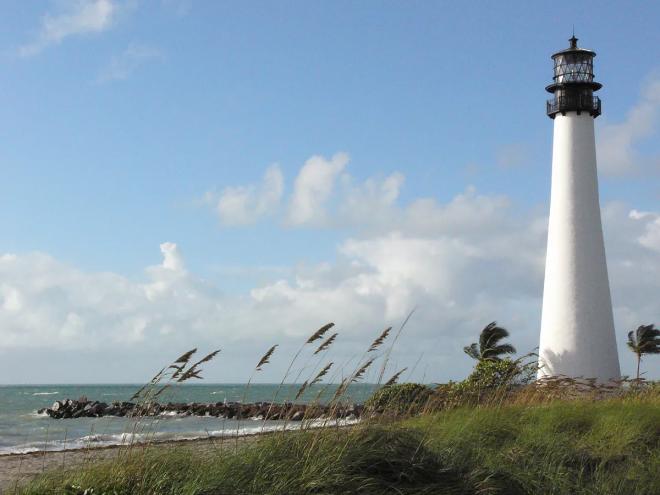 photo of a white lighthouse towering over dunes on the beach