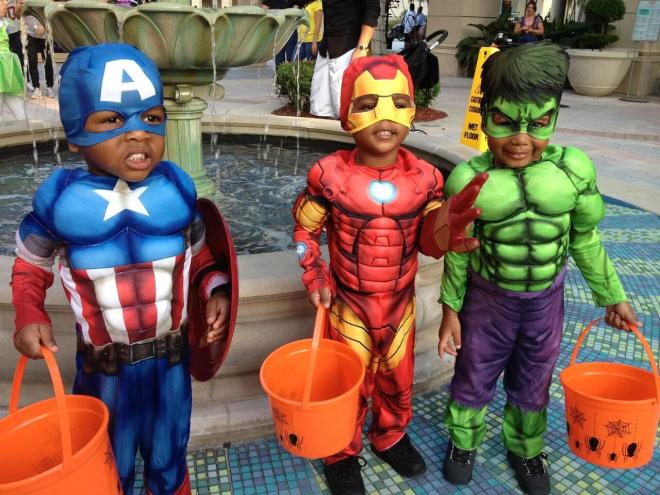 three li'l trick-or-treaters dressed in superhero costumes