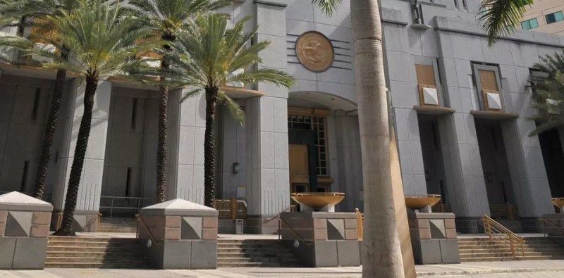 A white government building with three palm trees in front of it.
