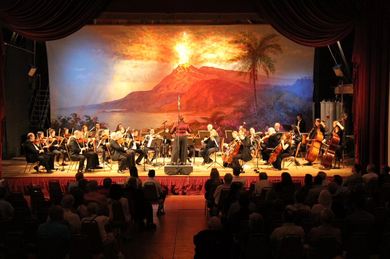 Photo of an orchestra playing in front of palm trees