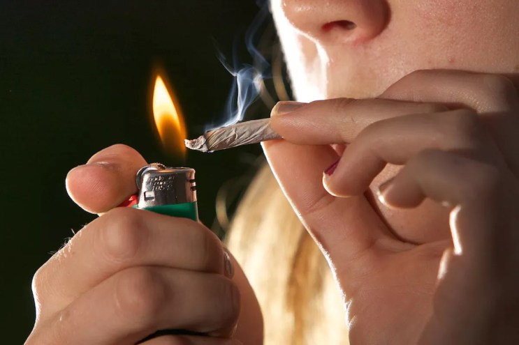 A woman lights a joint