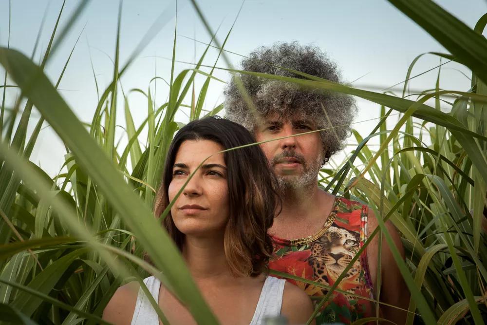 Photo of a an and a woman posing between plants