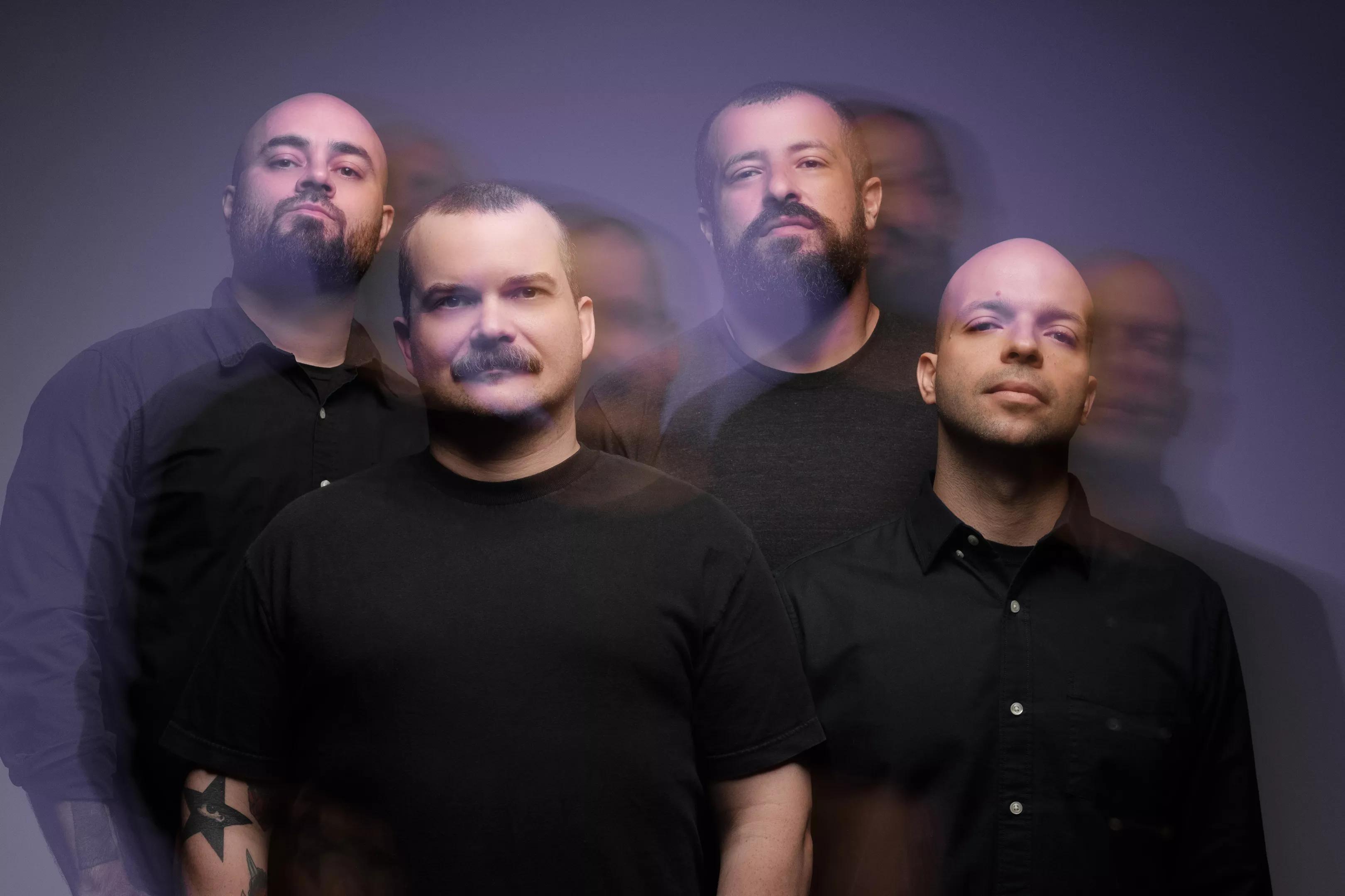 photo of four men looking at the camera wearing black shirts.