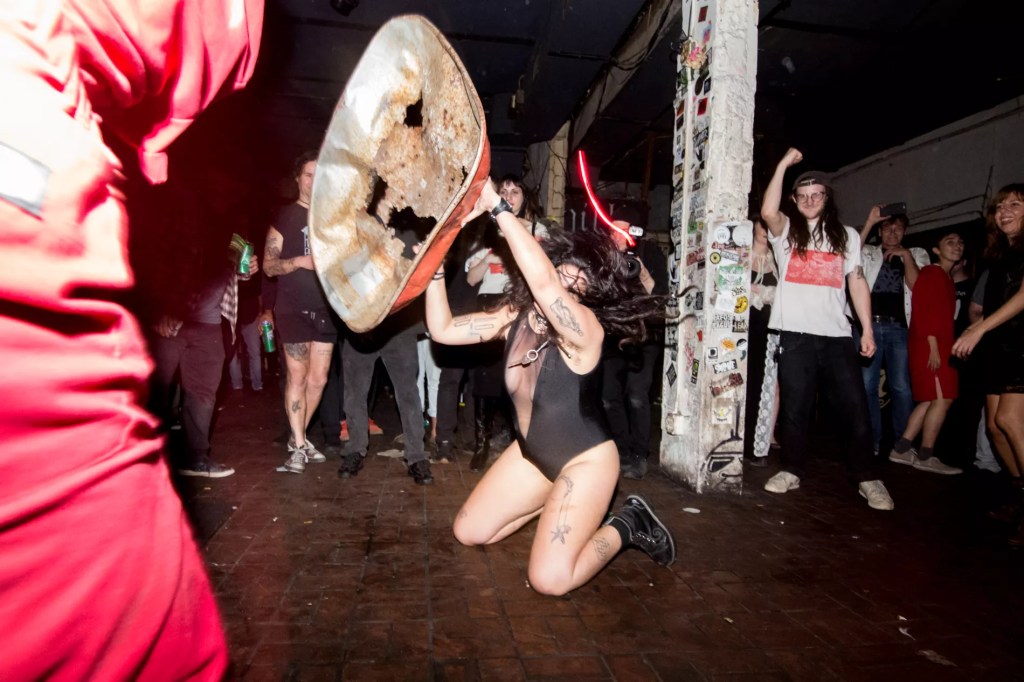 Photo of a woman on a stage pn her knees holding a metal structure