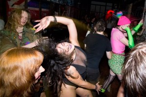 photo of a girl in a black and mesh bodysuit dancing in the middle of a crowd in a club.
