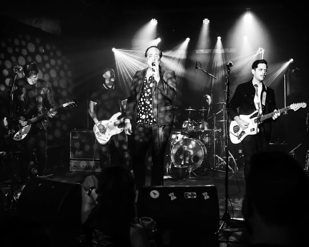 Black and white photo of a four piece rock band on stage in Miami