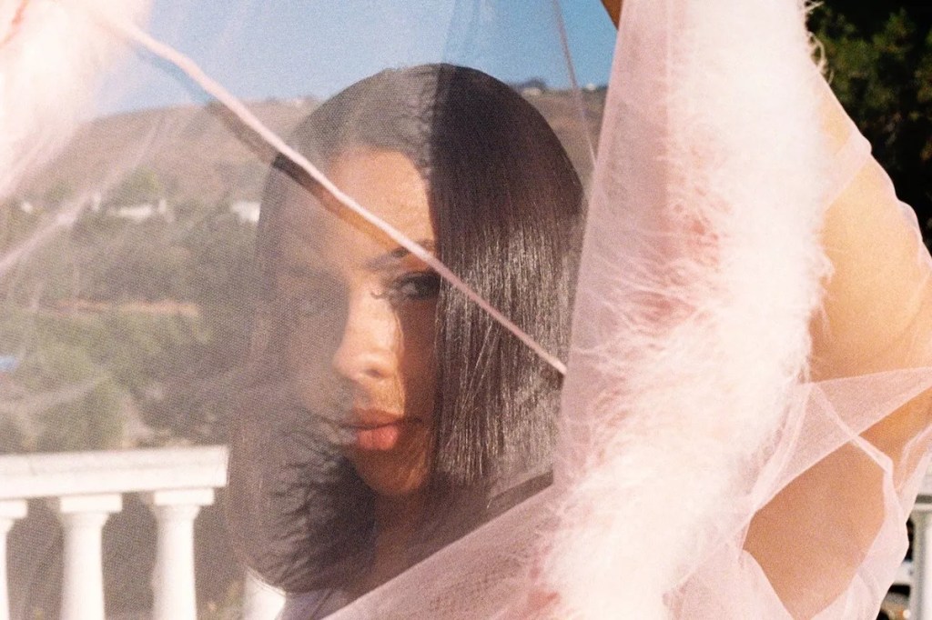photo of a woman on a balcony peeking through her sheer pink dress