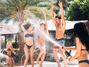 three people dance as someone sprays champagne on them