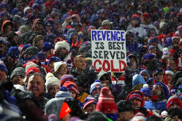 Bills fans in the snowy stands at Highmark Stadium during the December 17, 2022, 32-39 victory over the Miami Dolphins, holding up a sign that reads, "Revenge Is Best Served Cold"
