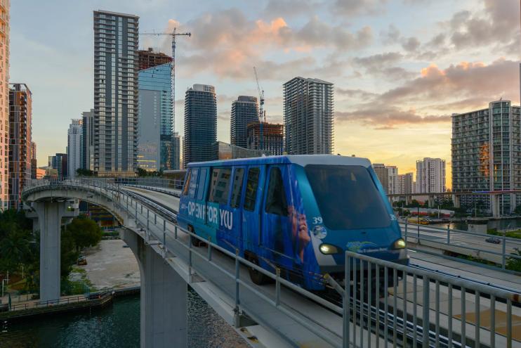 A blue Metromover train rides along the tracks in Miami