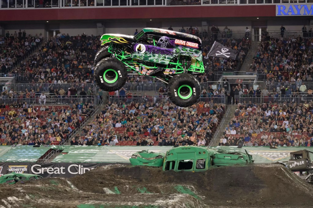 photo of a Monster Truck flying through the air in front of spectators inside an arena