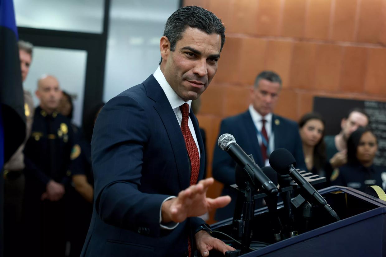 Miami Mayor Francis Suarez in a nifty suit extends an open hand in the direction of the camera