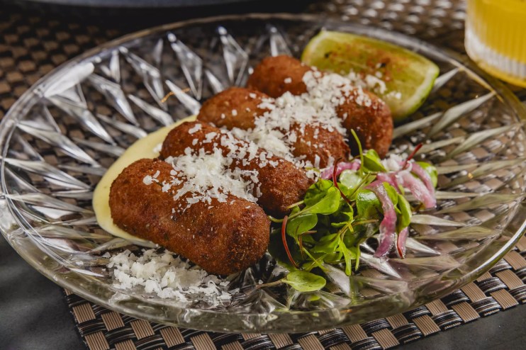 Social 27's fried chorizo croquetas topped with pecorino romano on a plate
