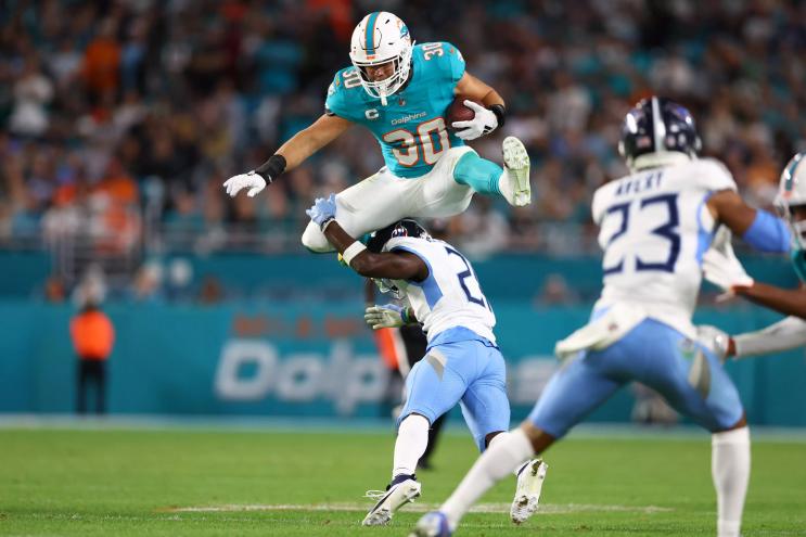 Miami Dolphins player jumping over a defender.