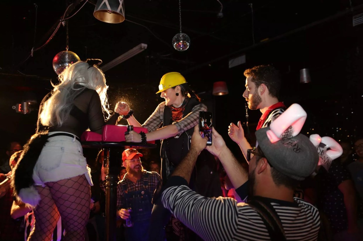 Two women arm wrestling as the crowd cheers them on