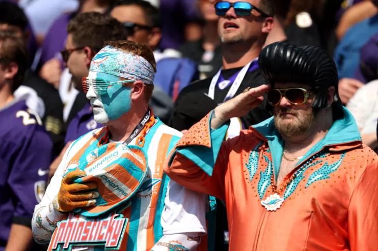 A Miami Dolphins fan in an Elvis Presley costumer salutes