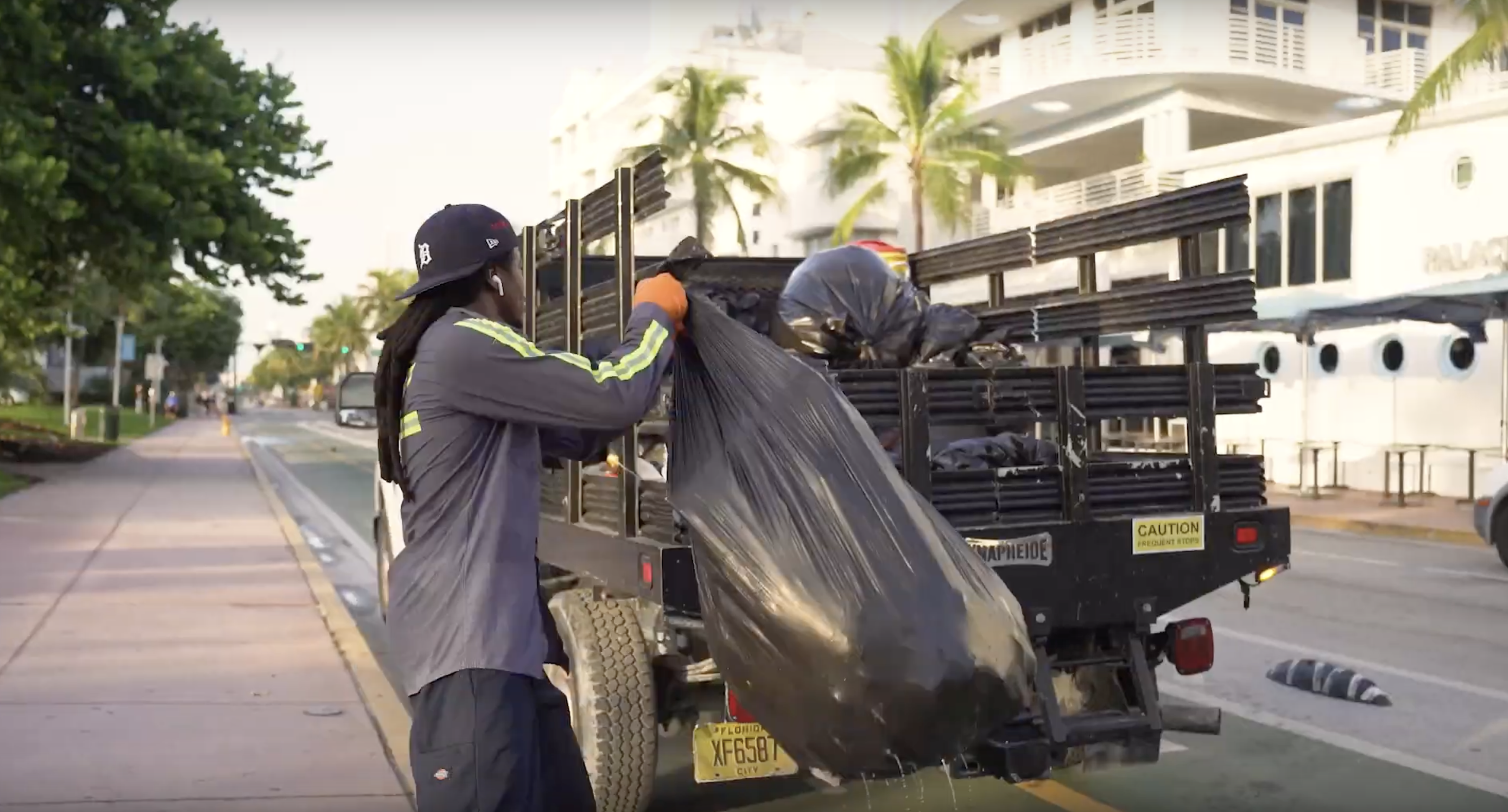 A South Florida garbage collection worker tosses trash into a truck's flatbed