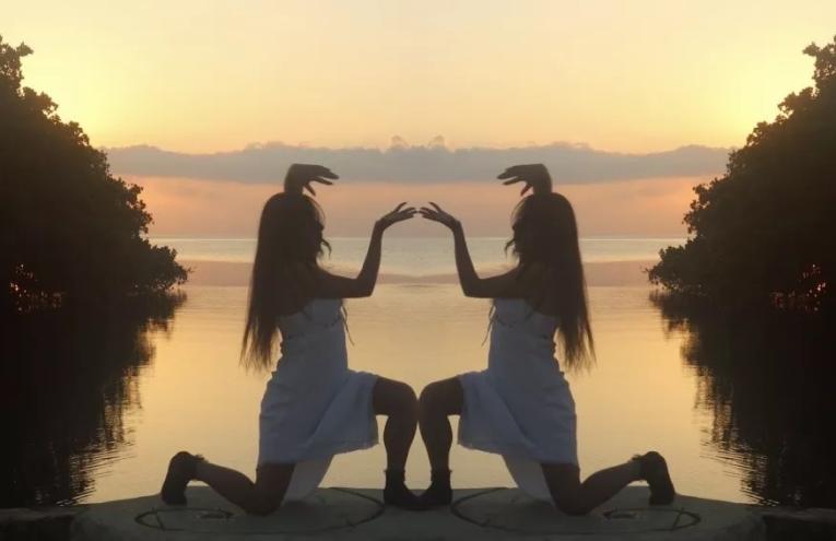 Still image from Caracoles en Cemento of a woman mirrored as she kneels with a sunset behind her