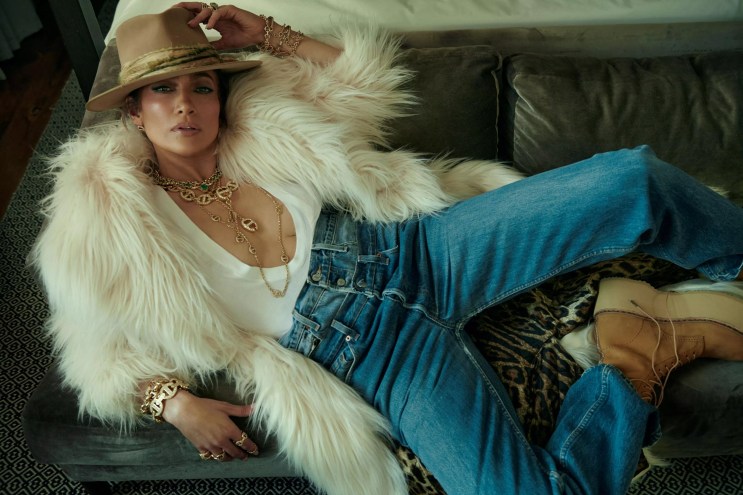Jennifer Lopez laying back in a white blouse and jeans
