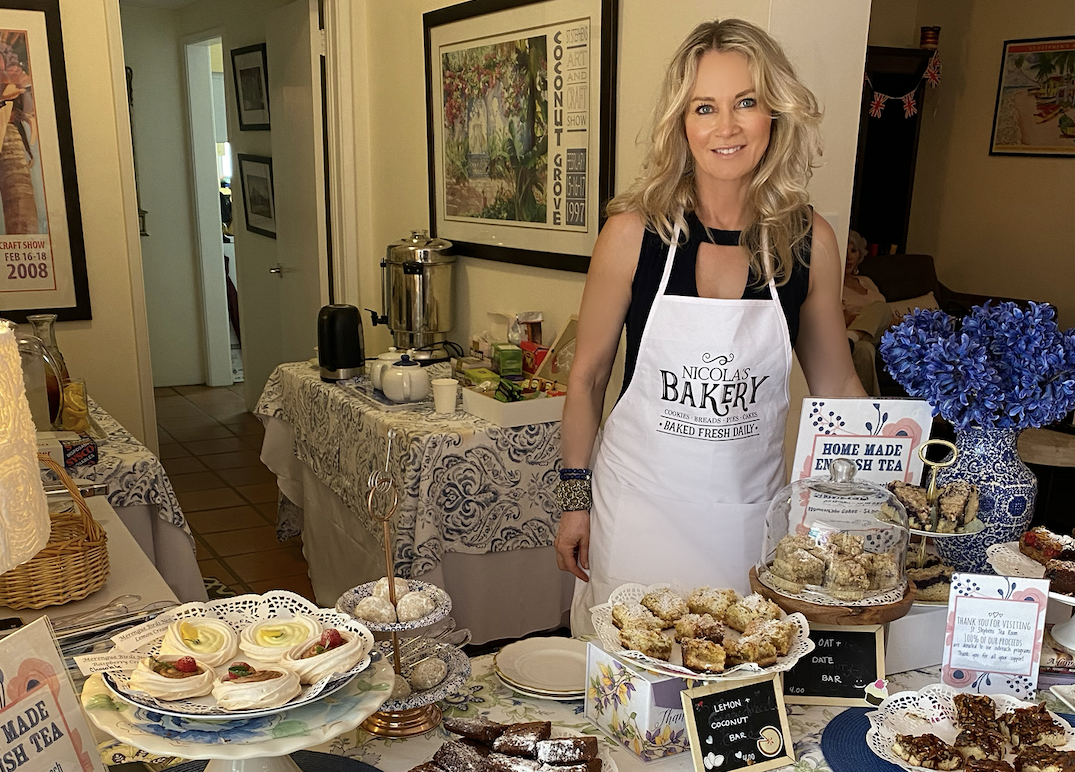 A blonde woman poses next to pastries on a table