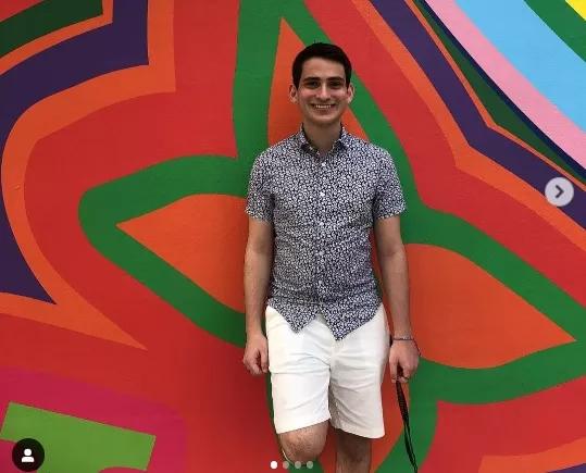 Danny Bishop smiling and standing against a colorful abstract art background.