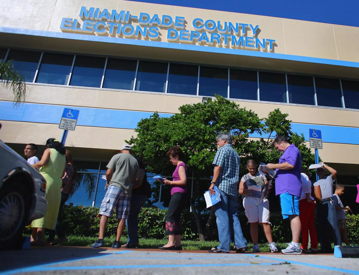A small group of residents stand outside a county elections building