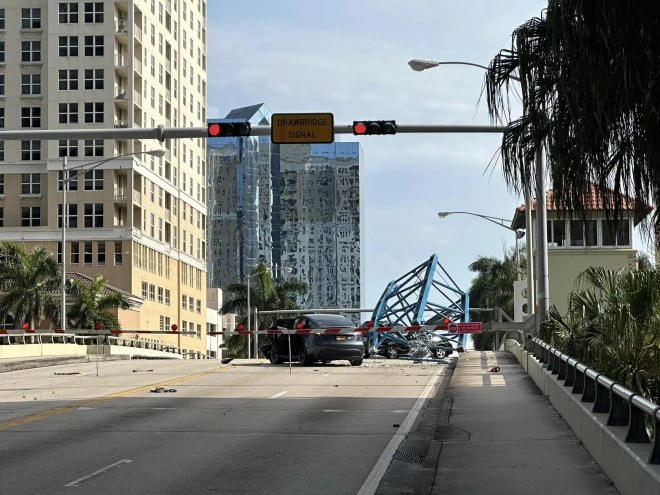 A broken off piece of a crane sits atop a vehicle in the middle of a Florida bridge after a construction accident