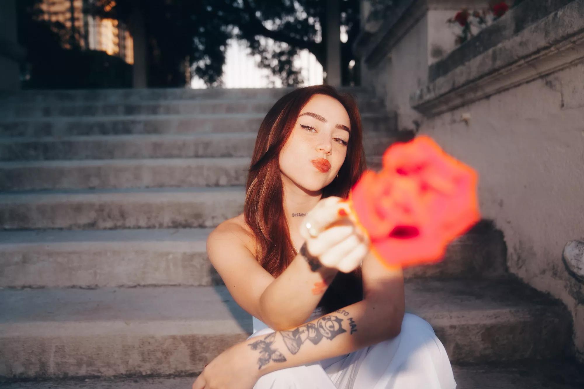 Nicki Nicole holding a flower toward the camera