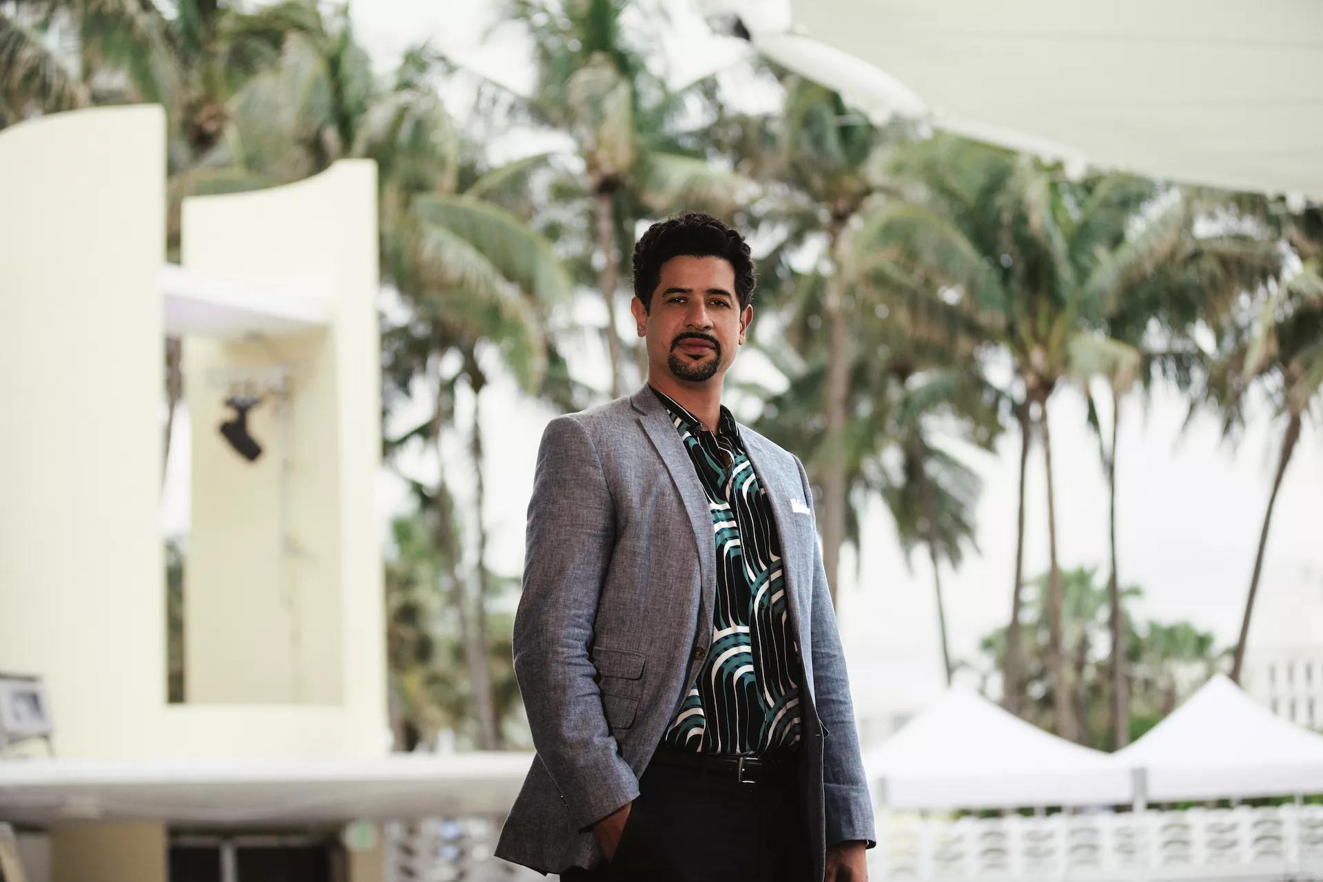 Adam Ganuza in a blazer in front of palm trees
