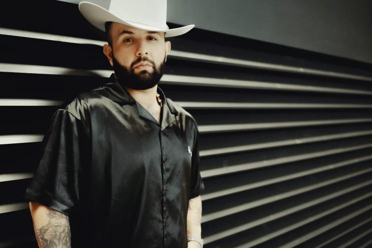 Carin León in a black shirt and white cowboy hat