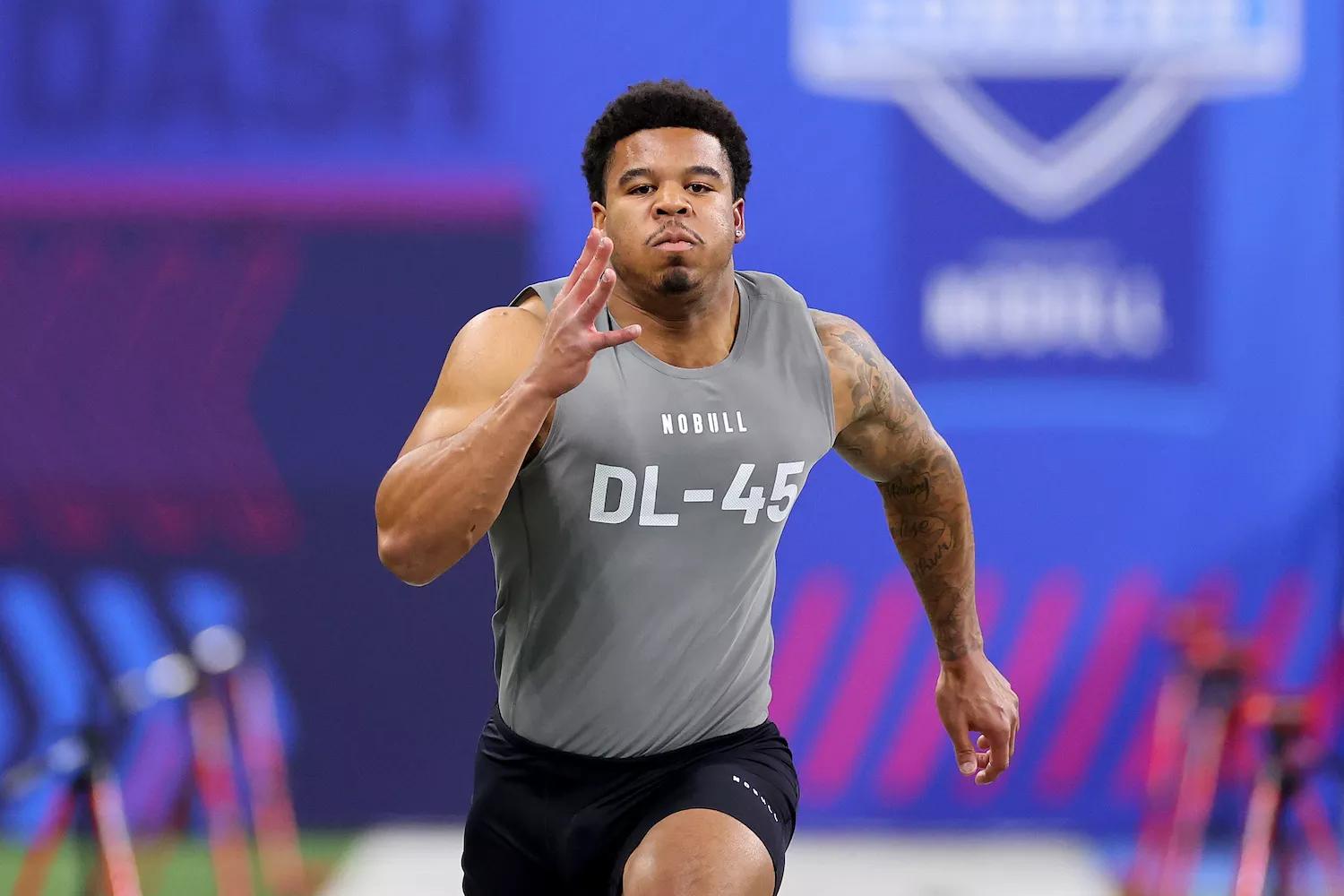 Head-on shot of a sprinting football player wearing black shorts and a sleeveless gray shirt