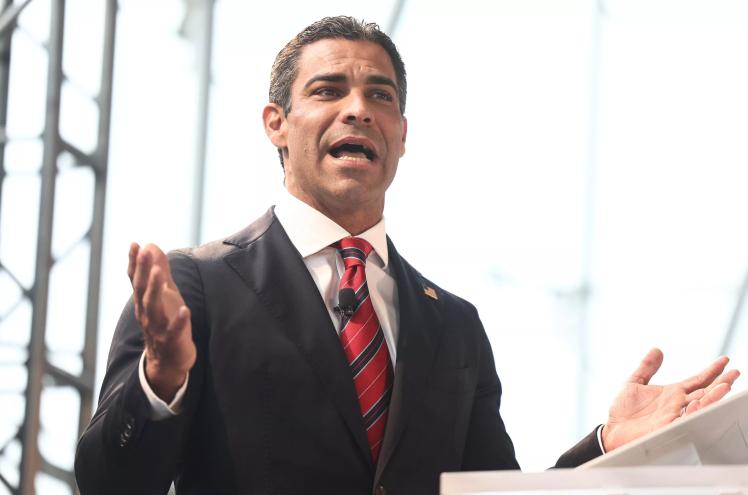 Dressed in a suit and red tie, Miami Mayor Francis Suarez extends his right hand and speaks