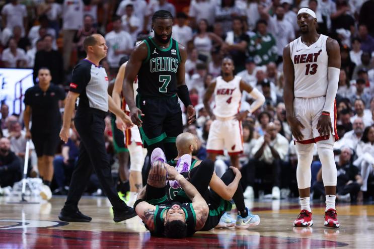 Jayson Tatum of the Celtics lies on the court, grasping his leg, apparently in pain