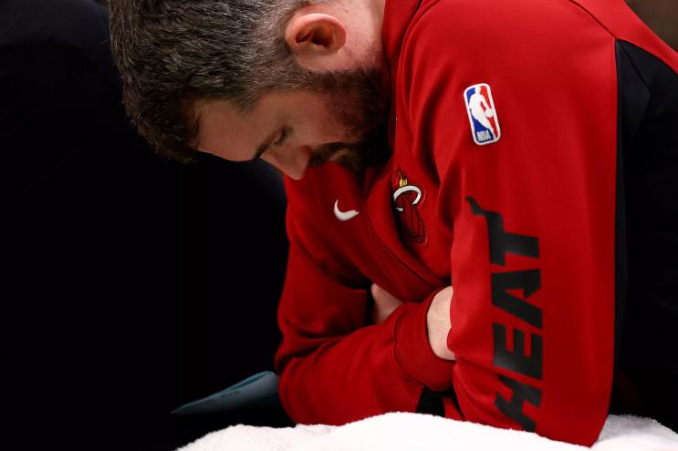 Miami Heat player Kevin Love stares down toward the floor from the bench during a playoff game