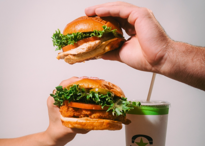 Two sandwiches being held in the air