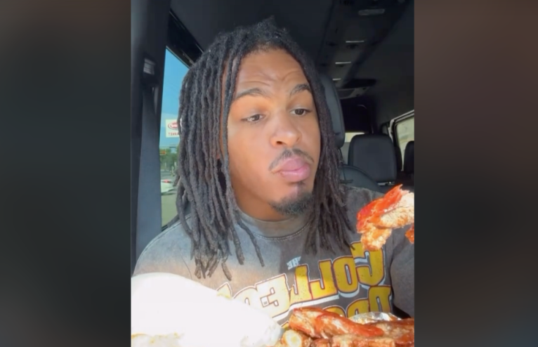 A man in a car holding ribs to eat