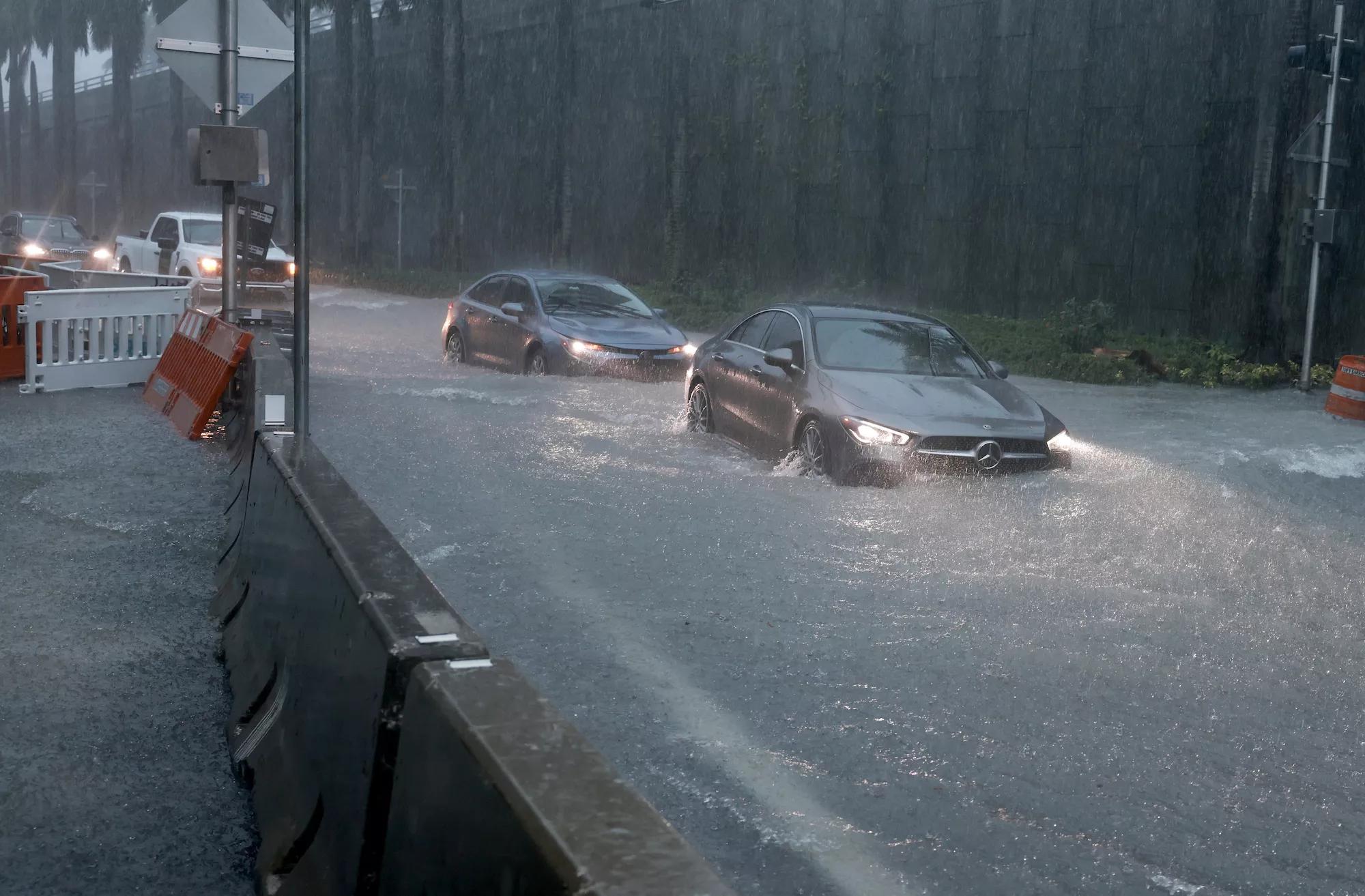 Vehicles make their way through a flooded street on June 12, 2024, in Aventura, Florida, as tropical moisture passes through the area.
