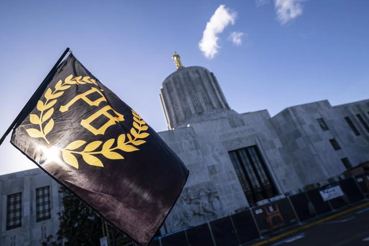A flag for the extremist Proud Boys group flies against a blue, clear sky