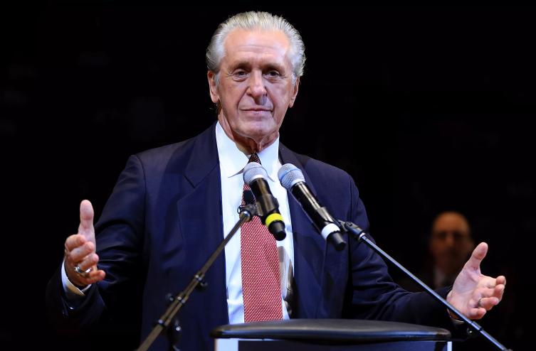 Pat Riley stands in a suit in front of a podium