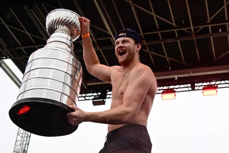 A shirtless Steven Lorentz holding the Stanley Cup trophy