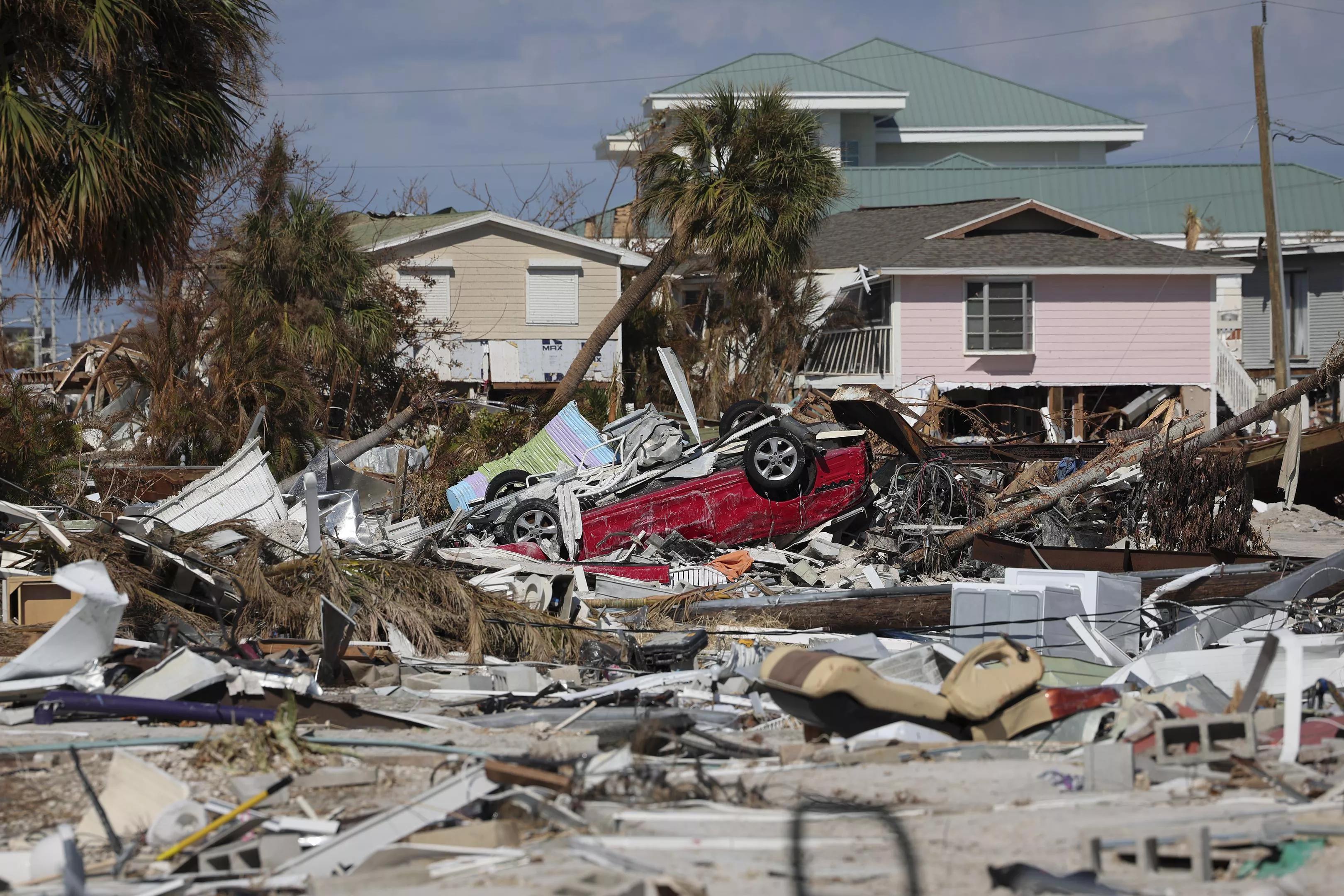 Building remnants, giant piles of debris, and an overturned car in the wake of Hurricane Ian