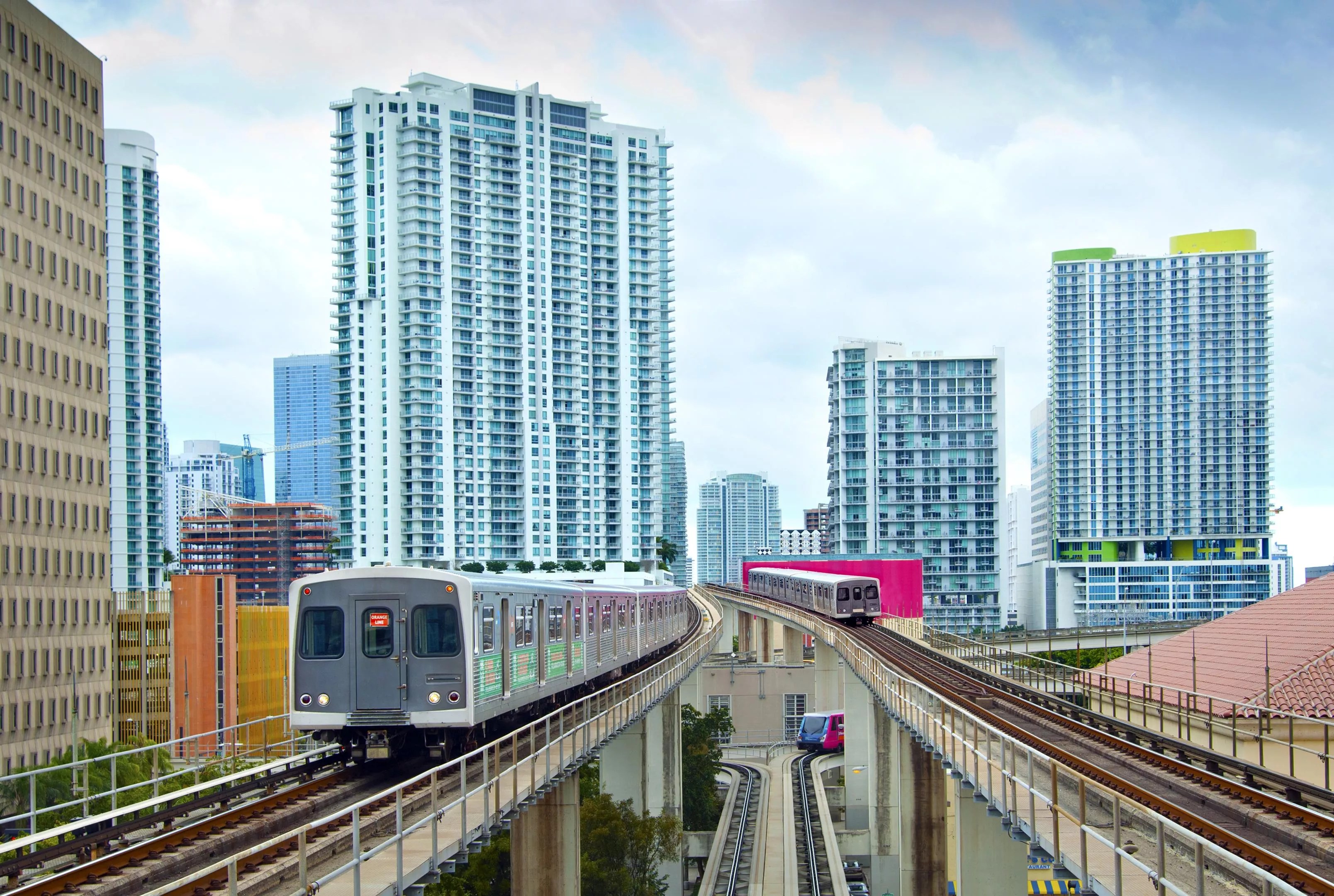 Two metro trains on elevated platforms with the Miami skyline in the background