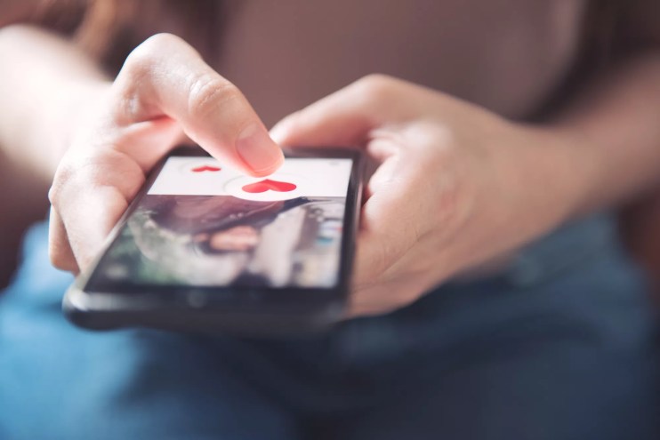 Hands on a phone with a dating app on the screen