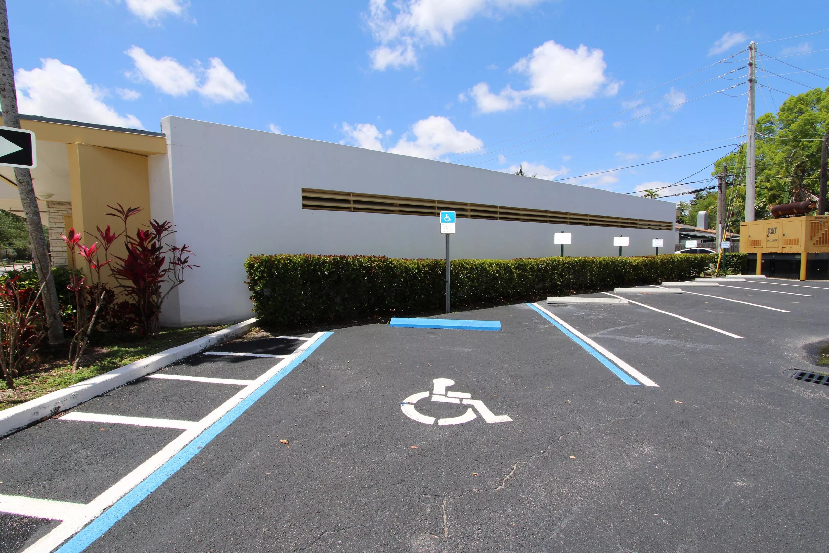 A set disabled parking lot spaces in front of a city hall building, with blue skies in background