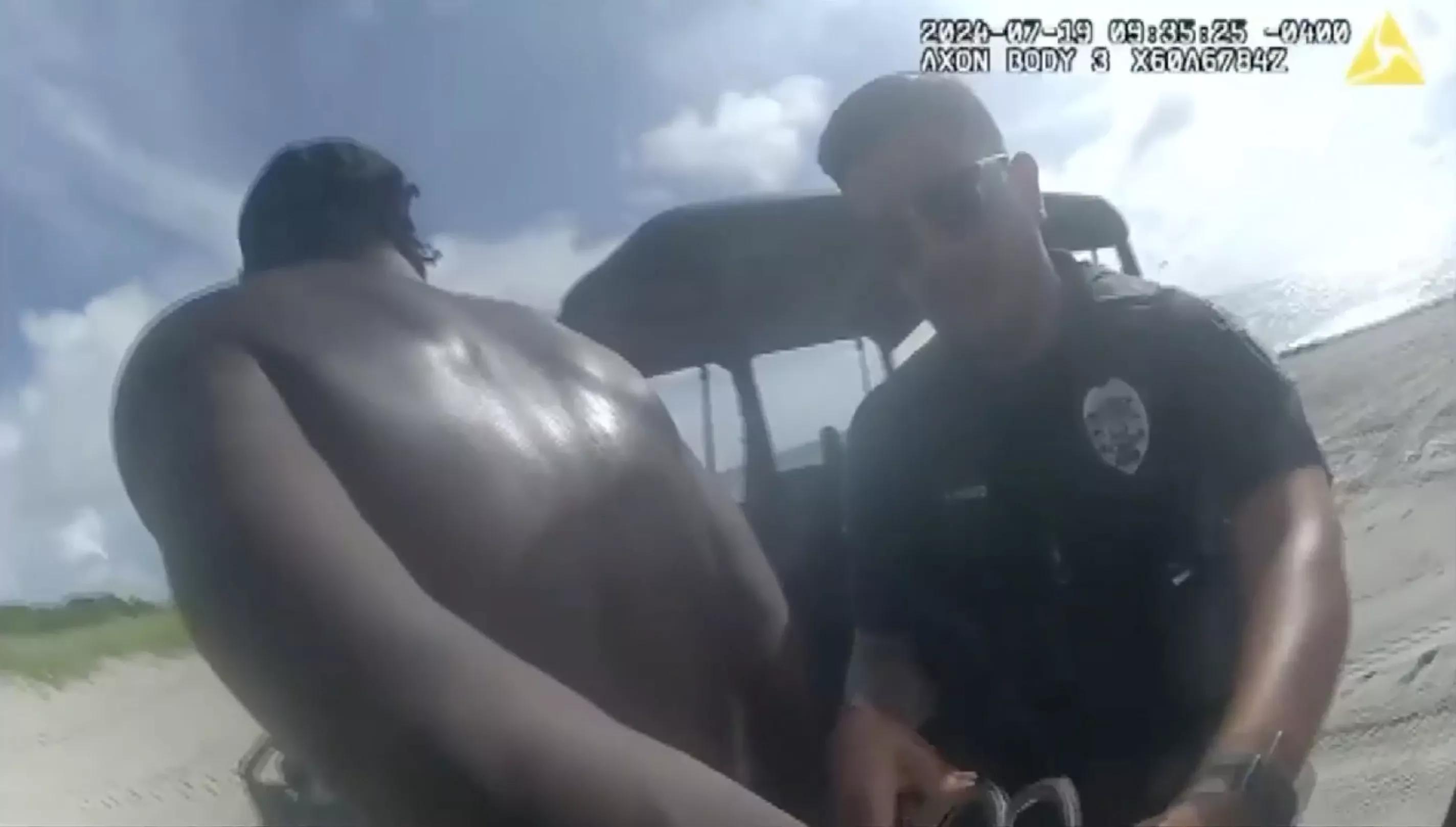 body cam screenshot of a police officer cuffing a suspect on a beach