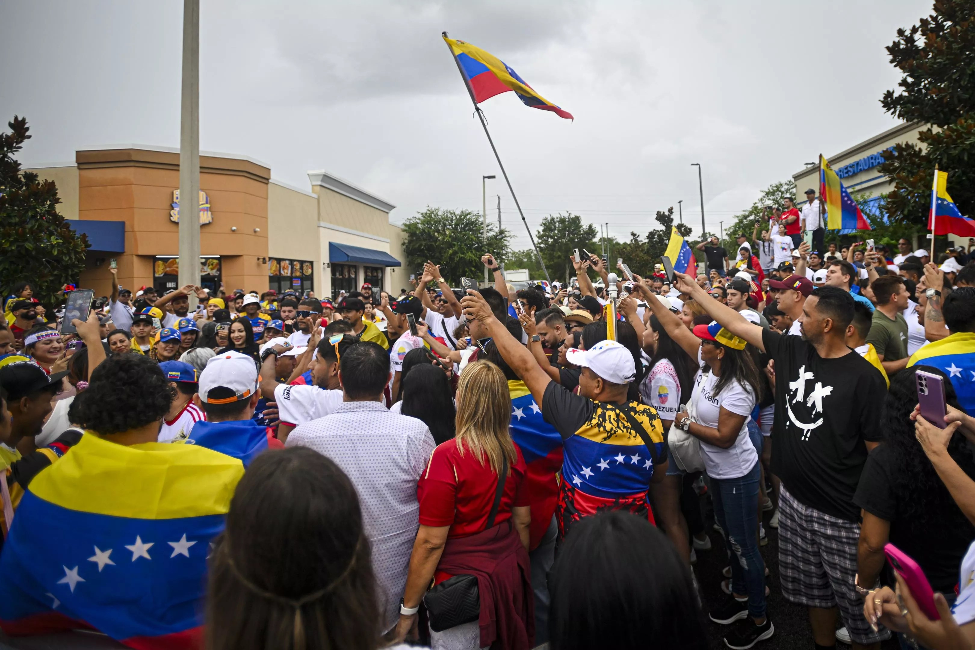 A crowd packs together on an Orlando street, waving Venezuelan flags